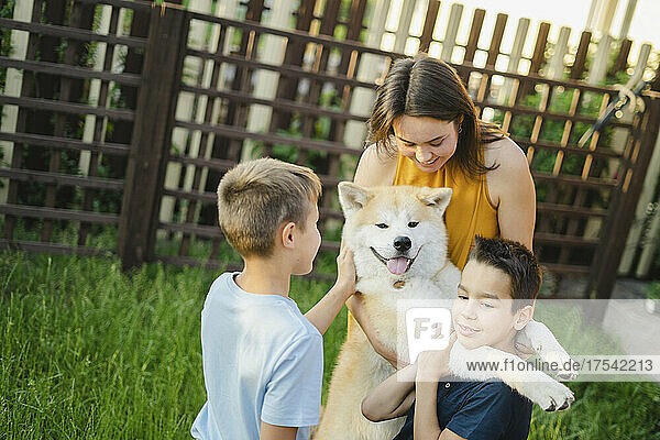 Happy family playing with Akita dog on grass