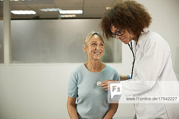 Doctor with curly hair examining senior patient in medical room