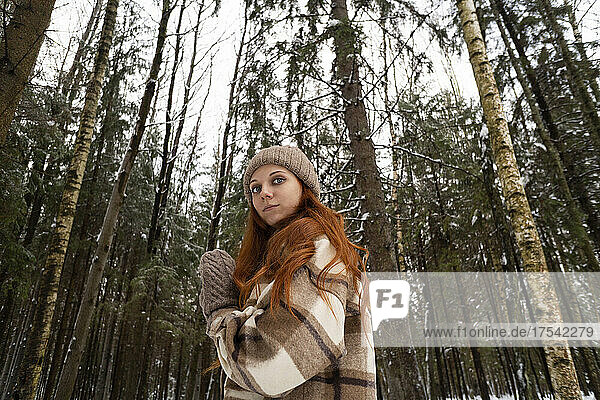 Confident redhead woman in front of trees in forest