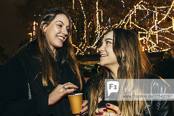Cheerful young friends enjoying coffee at night
