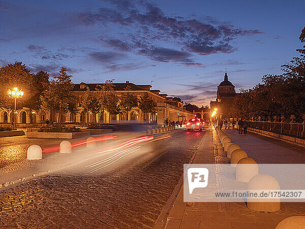 Spain  Community of Madrid  Aranjuez  Blurred motion of cars driving along cobblestone street at dusk