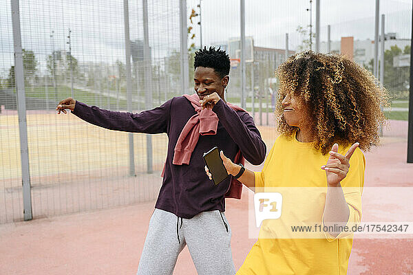 Young woman dancing with friend at sports field
