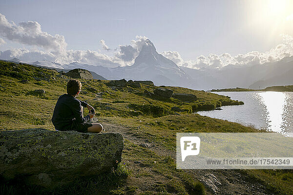 Hiker sitting on rock looking at Matterhorn mountain  Zermatt  Switzerland