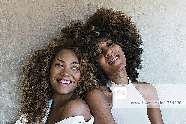 Smiling young women leaning on each other