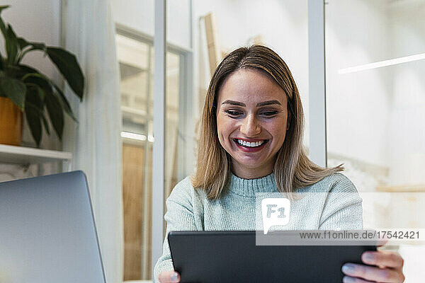 Glückliche Geschäftsfrau nutzt Tablet-PC im Studio