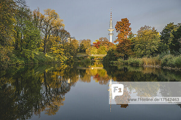 Germany  Hamburg  Autumn trees reflecting on surface of shiny lake in Wallanlagen park