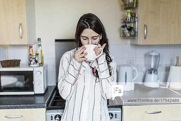 Frau trinkt Tee in der heimischen Küche