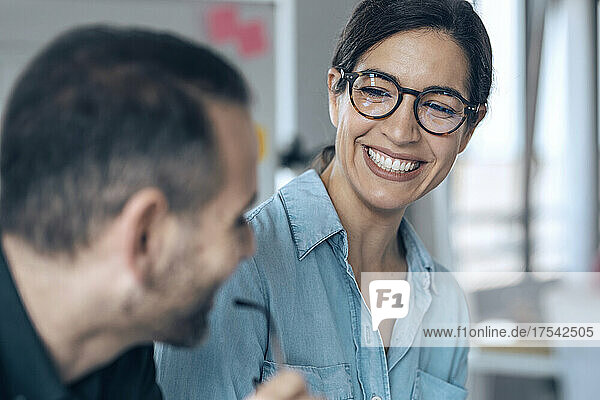 Happy businesswoman looking at colleague in office