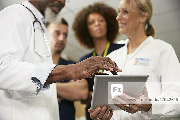 Arzt nutzt Tablet-PC mit Kollegen bei Besprechung im Krankenhaus