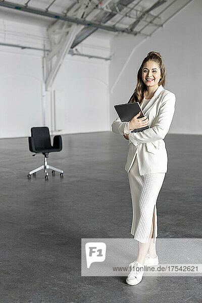 Smiling businesswoman holding tablet PC at factory