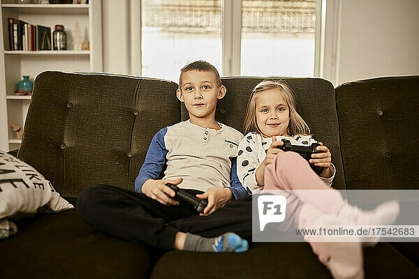 Sibling playing video game through joystick at home