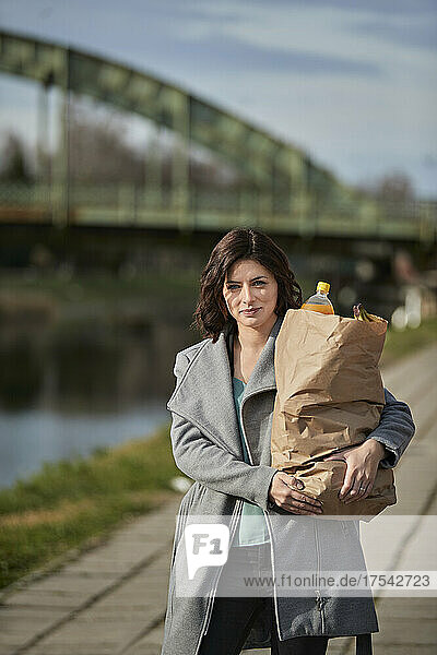 Frau trägt Lebensmittel in Papiertüte auf Fußweg