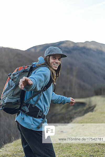 Cheerful man with backpack hiking in mountains