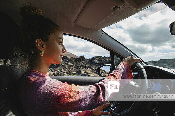 Young woman driving car on sunny day