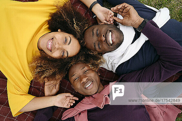 Smiling multiracial friends lying on blanket in park