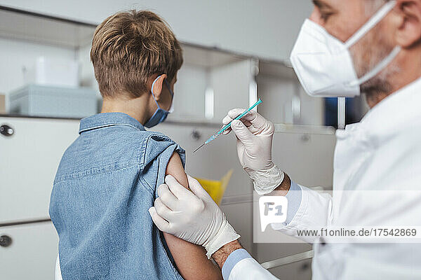 Healthcare worker administering boy with COVID-19 vaccine at vaccination center