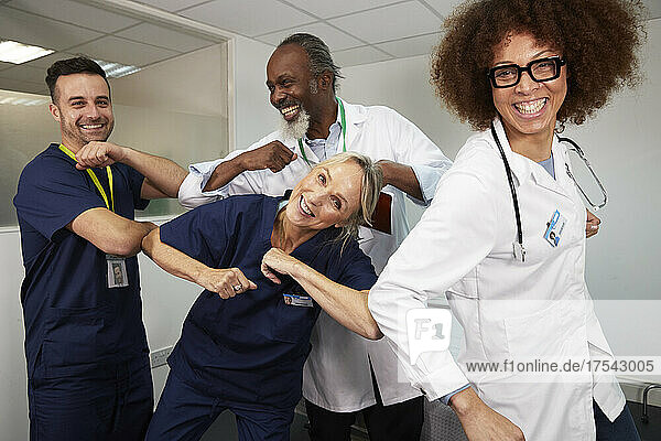 Playful multiracial medical workers giving elbow bumps to each other at hospital