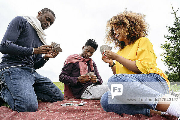 Young friends playing cards in park