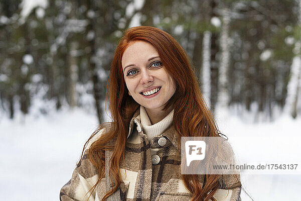Happy redhead woman in winter forest