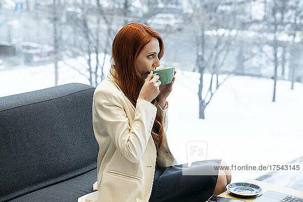 Berufstätige Frau trinkt Kaffee auf dem Sofa in der Bürokantine