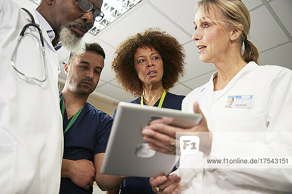 Ärztin erklärt Kollegen über Tablet-PC bei Besprechung im Krankenhaus