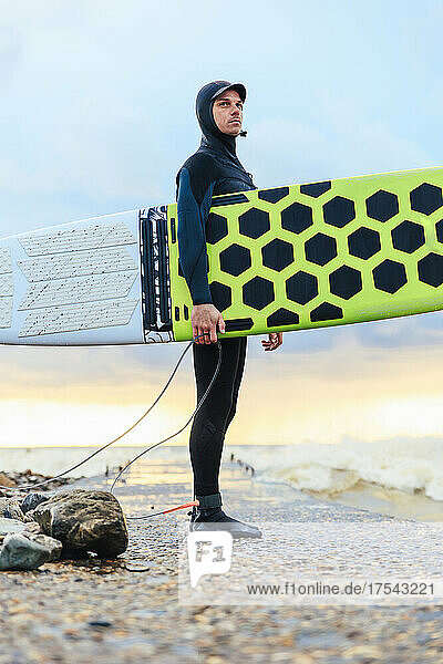 Confident surfer standing with surfboard on pier