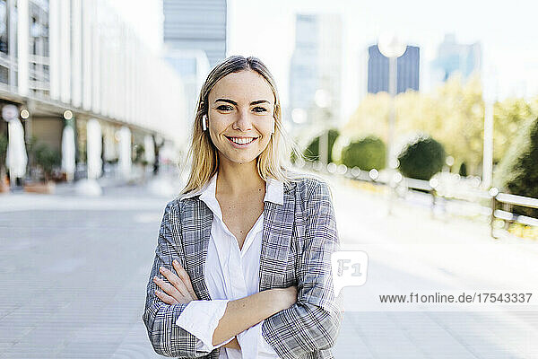 Happy blond young businesswoman standing with arms crossed