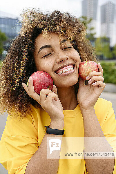 Smiling woman with eyes closed holding apples