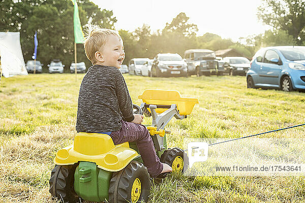 Smiling boy (18-23Êmonths)Êsitting on toy bulldozer outdoors