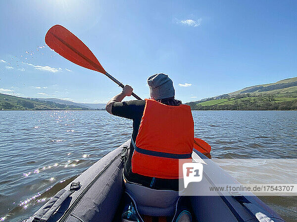 Rear view of woman kayaking on lake on sunny day