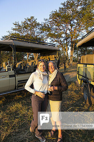 Two women  a mature woman and her mother  standing side by side at sundown on safari.