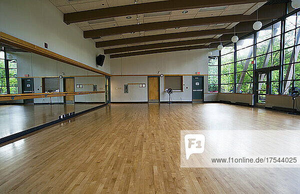 A dance ballet studio with a sprung wooden floor  barre and wall mirrors.