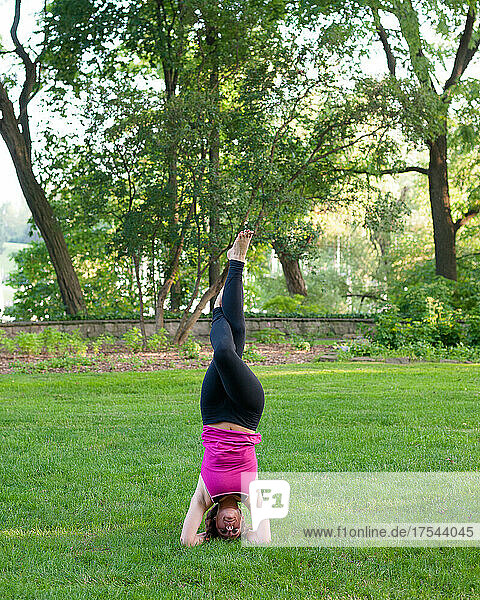 Woman balancing in yoga pose in park.