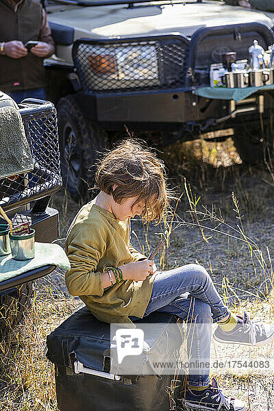 8 year old boy sitting near safari vehicles  Okavango Delta  Botswana