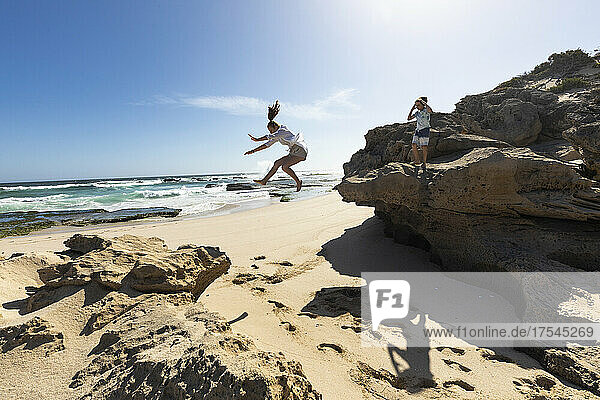 South Africa  Western Cape  Girl (16-17) jumping off rock at beach in Lekkerwater Nature Reserve
