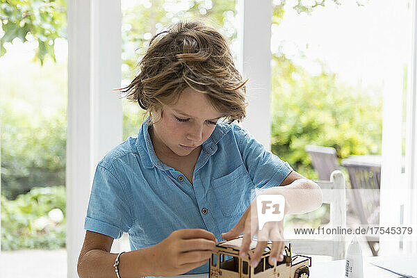 Boy (8-9) building wooden toy car at home
