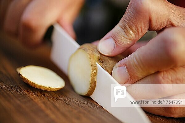Badische Küche  Topinambur (Helianthus tuberosus)  Erdapfel  Erdbirne  Knollen schneiden  Männerhände  Messer  Holzbrett  Deutschland  Europa