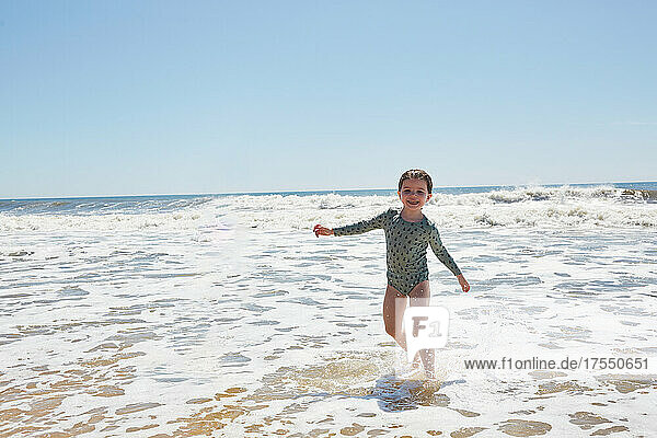 Portrait of smiling girl (2-3) playing in sea waves