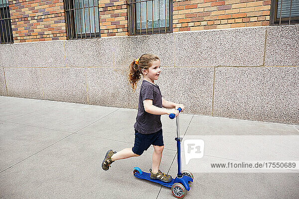 USA  New York  New York City  Girl (2-3) riding push scooter on sidewalk