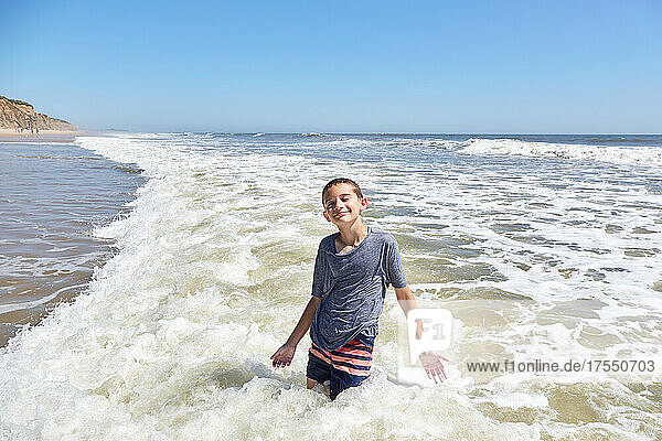 Smiling boy (8-9) in sea waves