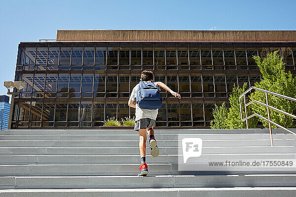 USA  New York  New York City  Rear view of boy (8-9) with backpack running up school steps