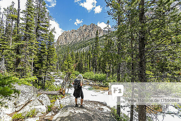 USA  Idaho  Stanley  Senior female hiker looking at rushing stream in Sawtooth Mountains