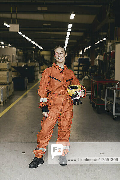 Porträt einer lächelnden Arbeiterin in Arbeitsschutzkleidung in einer Fabrik
