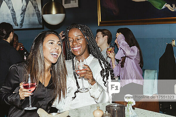 Glückliche weibliche und männliche Freunde trinken Wein während einer Party in einer Bar