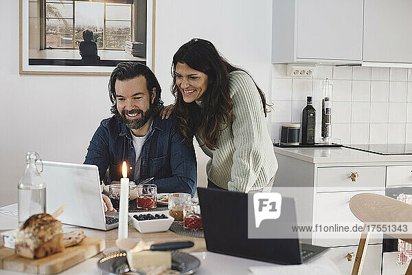 Lächelndes reifes Paar benutzt Laptop zu Hause