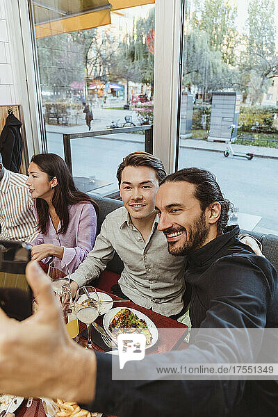Lächelnder Mann macht Selfie mit männlichem Freund in einer Bar
