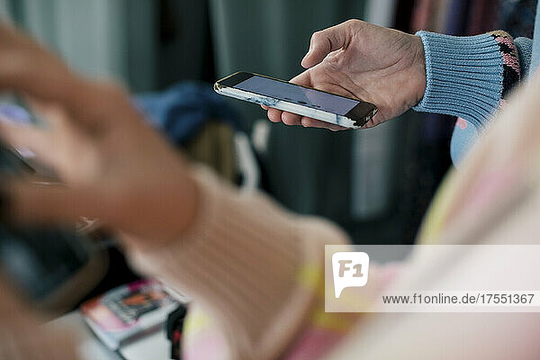 Ausgeschnittenes Bild einer Besitzerin  die ein Smartphone in einer Boutique benutzt