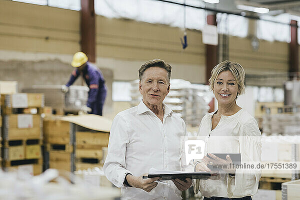 Porträt eines älteren Geschäftsmannes mit Tochter in einem Fabriklager