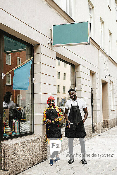 Happy male and female coworkers standing outside barber shop