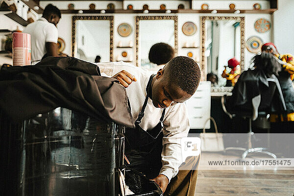 Junger männlicher Friseur öffnet Schublade im Friseursalon
